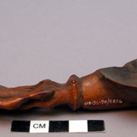 Wooden spoon, handle carved in human effigy: hands resting on flexed knees, shor