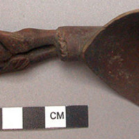 Wooden spoon, handle carved in human effigy: hands resting on flexed kneese no h