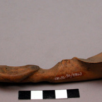 Wooden spoon, handle carved in human effigy: hands resting on flexed knees, sadd