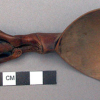 Wooden spoon, handle carved in human effigy: hands resting on flexed knees, coni