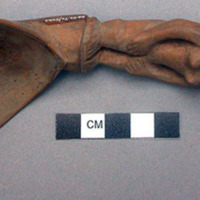 Wooden spoon, handle carved in human effigy: hands resting on flexed knees, fema