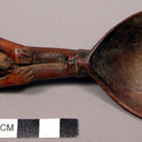Wooden spoon, handle carved in human effigy: hands resting on flexed knees, head