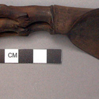 Wooden spoon, handle carved in human effigy: hands resting on flexed knees, turb