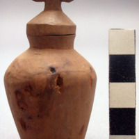 Small carved wooden jar with plugged bottom and stopper which seems to be non-re